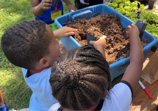 2 children digging in dirt at summer camp outside