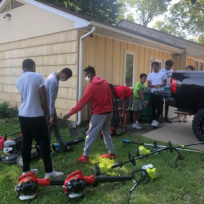 Group on young men working on lawn care at a residence.