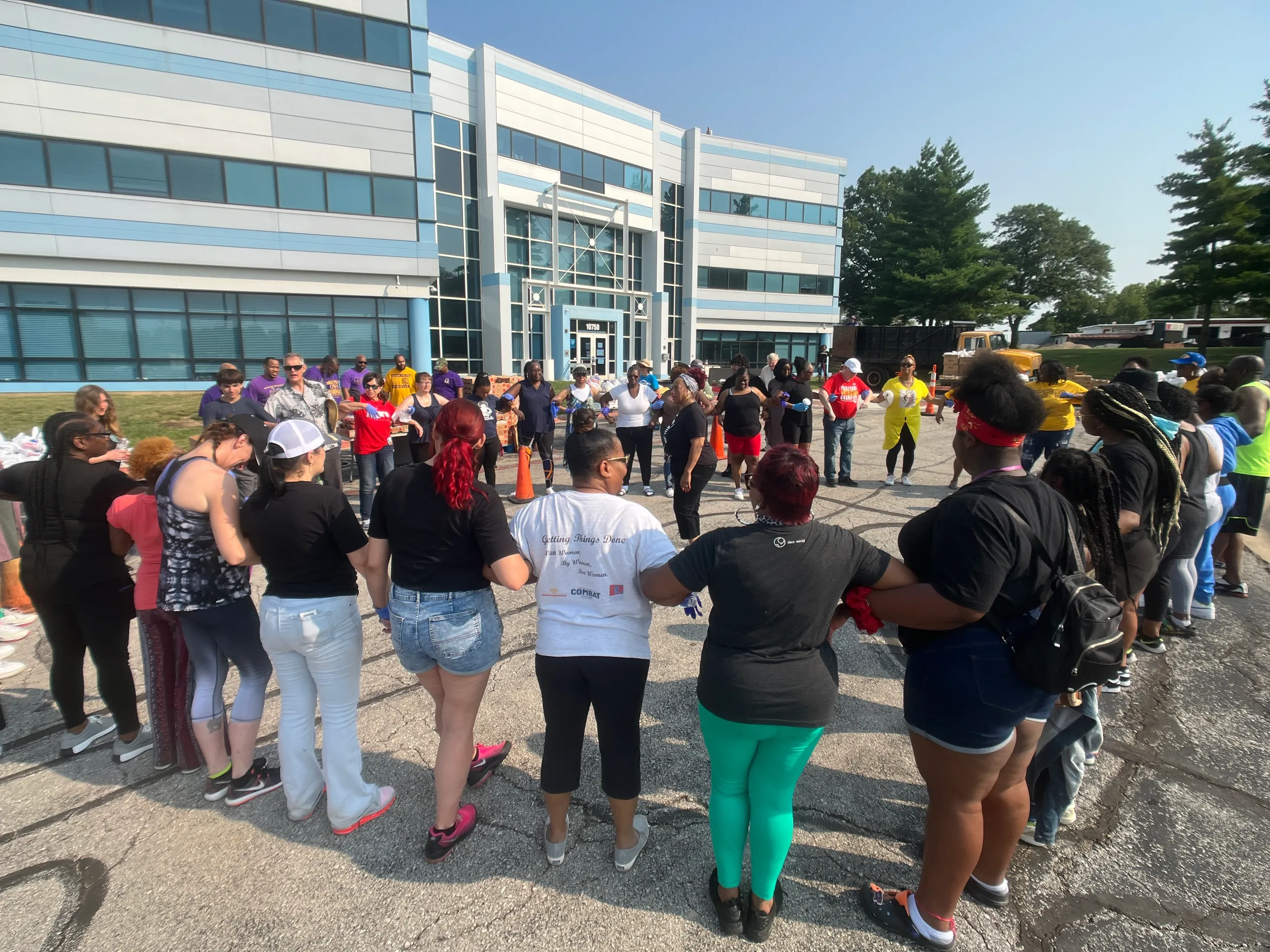 partner-with-us People in the community standing in a circle holding hands outside a city building
